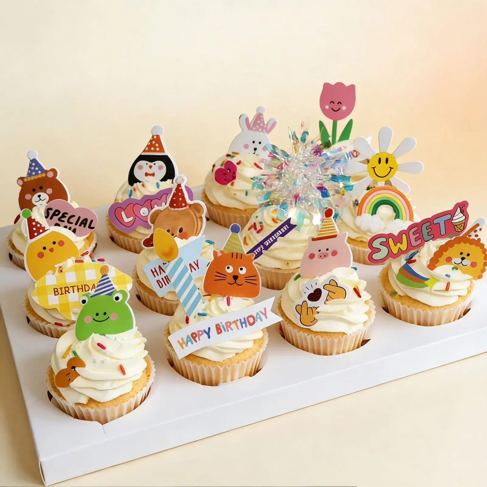 Assorted birthday cupcakes with cream frosting and playful cartoon toppers in bright colors
