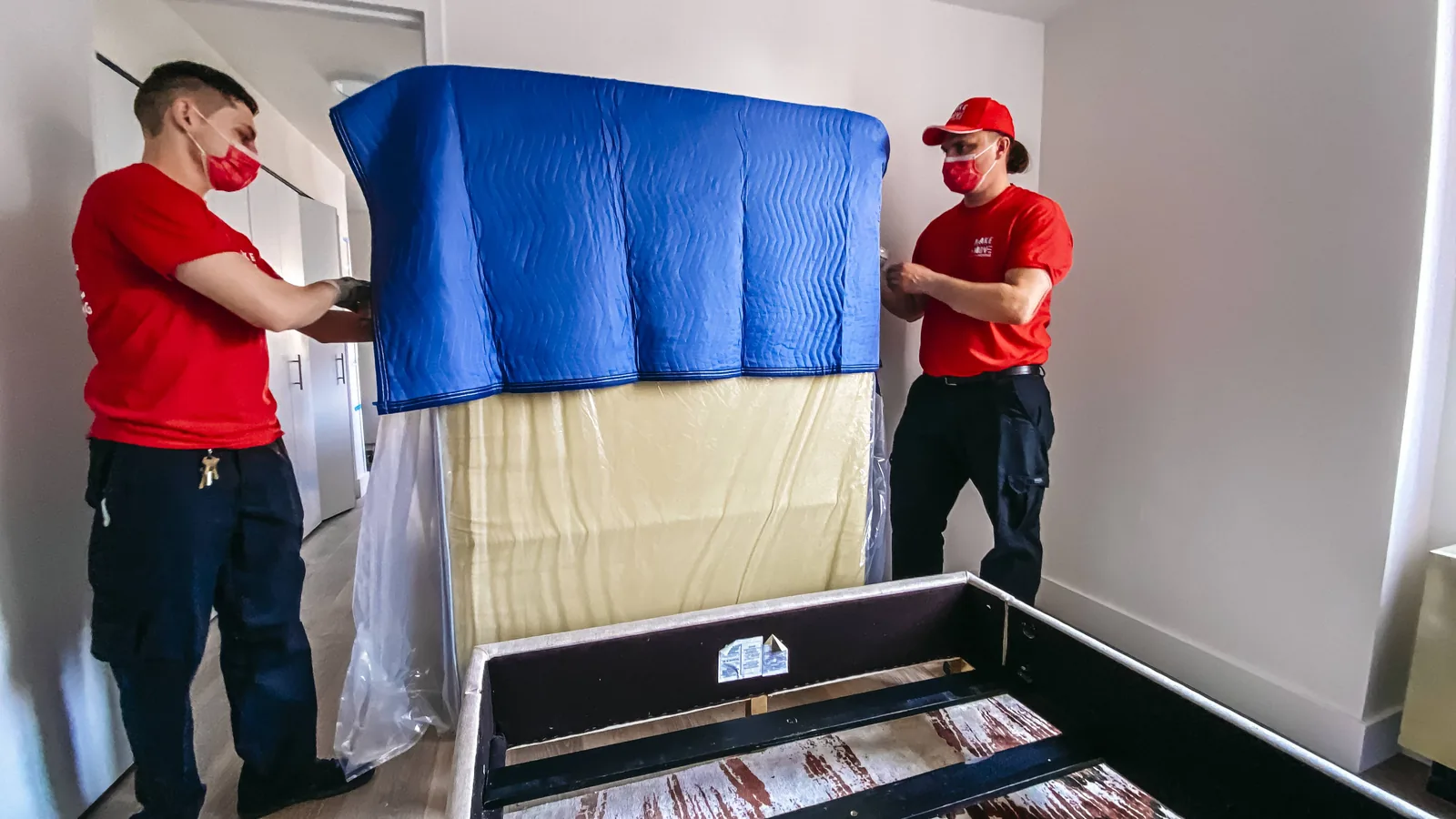 Moving company workers wrapping a mattress with protective covering