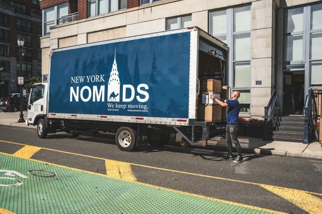 New York Nomads moving truck with worker loading boxes on a city street