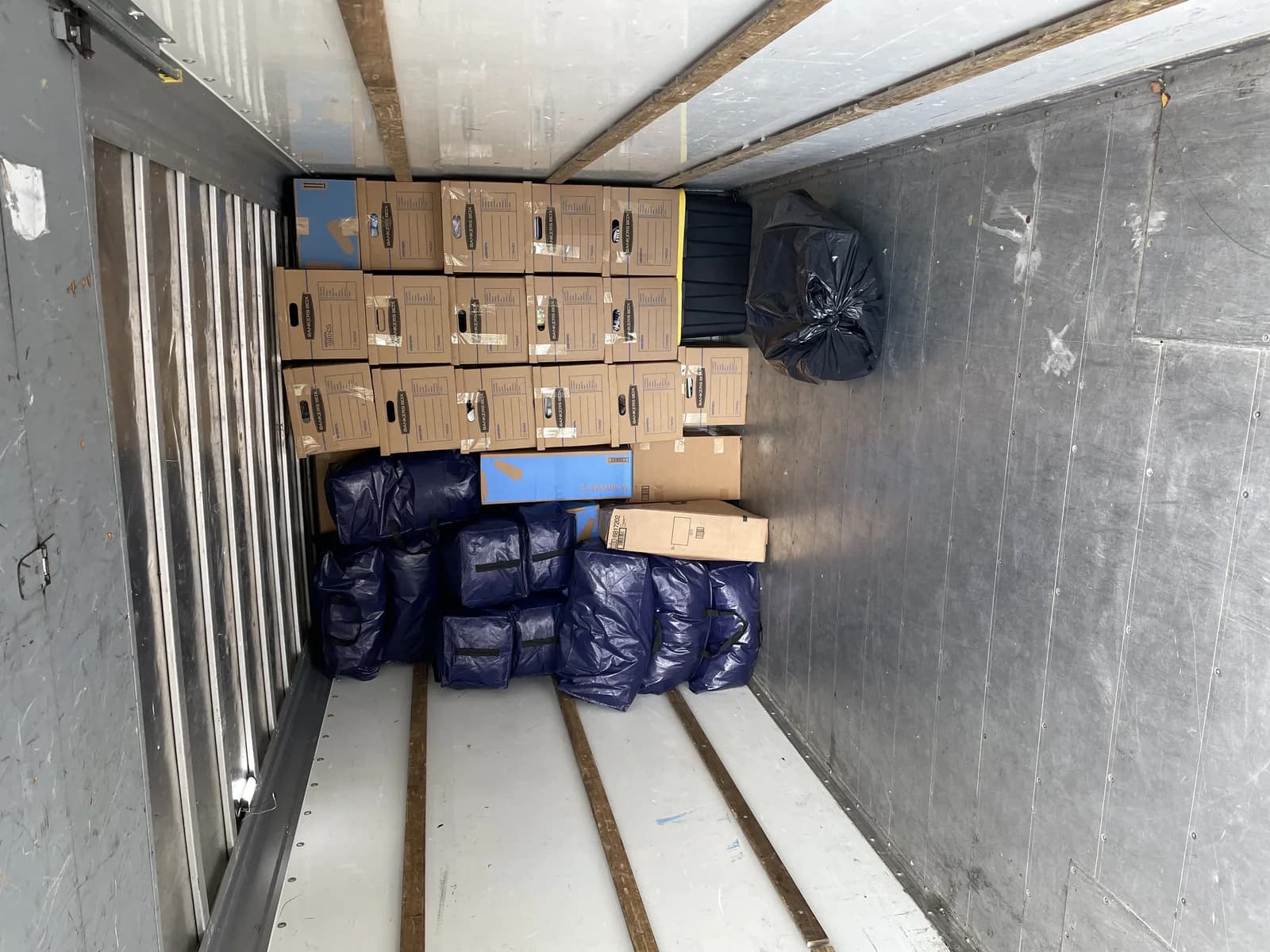 Moving truck interior packed with stacked boxes and padded furniture bags