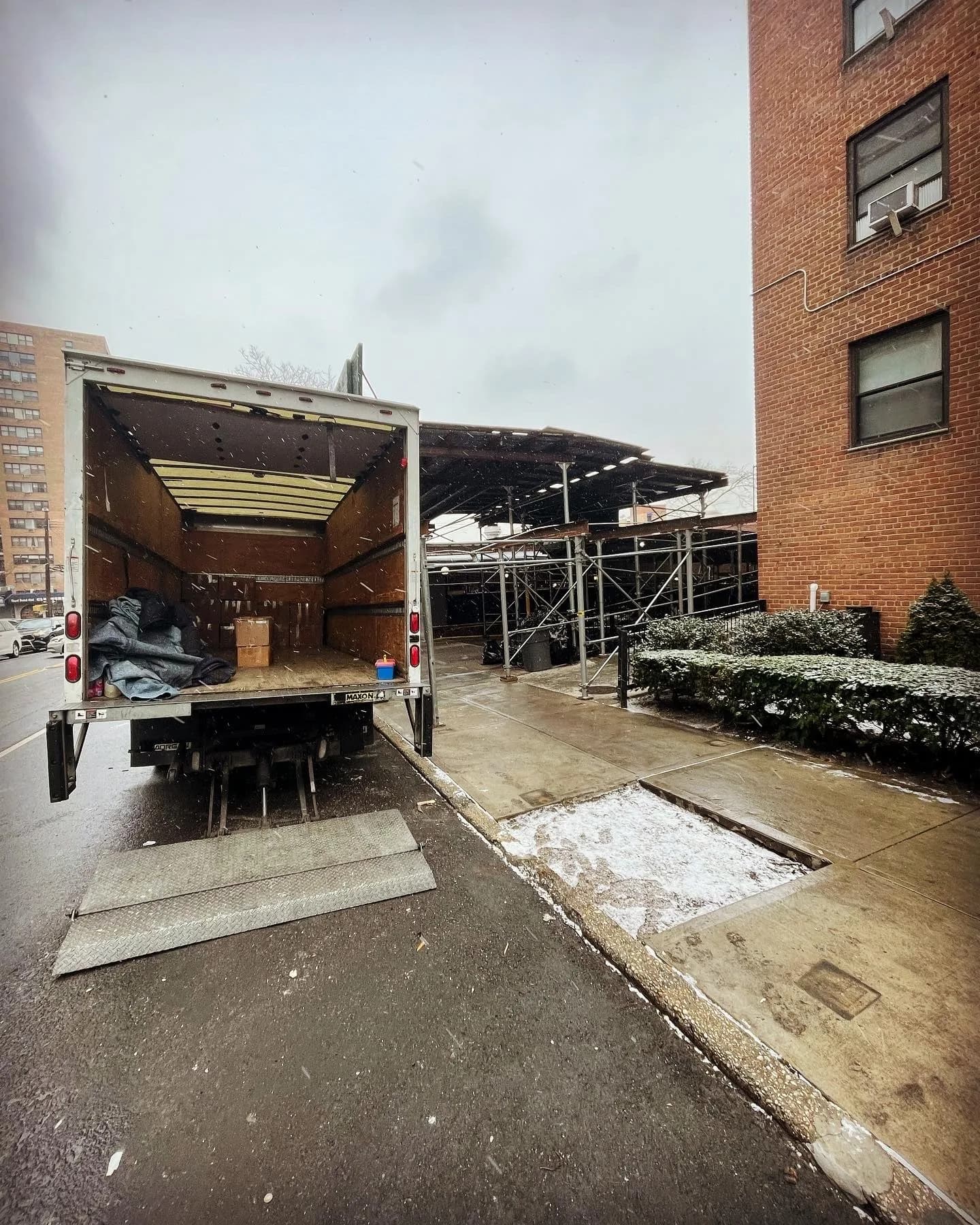 Open moving truck parked at brick building entrance during relocation work
