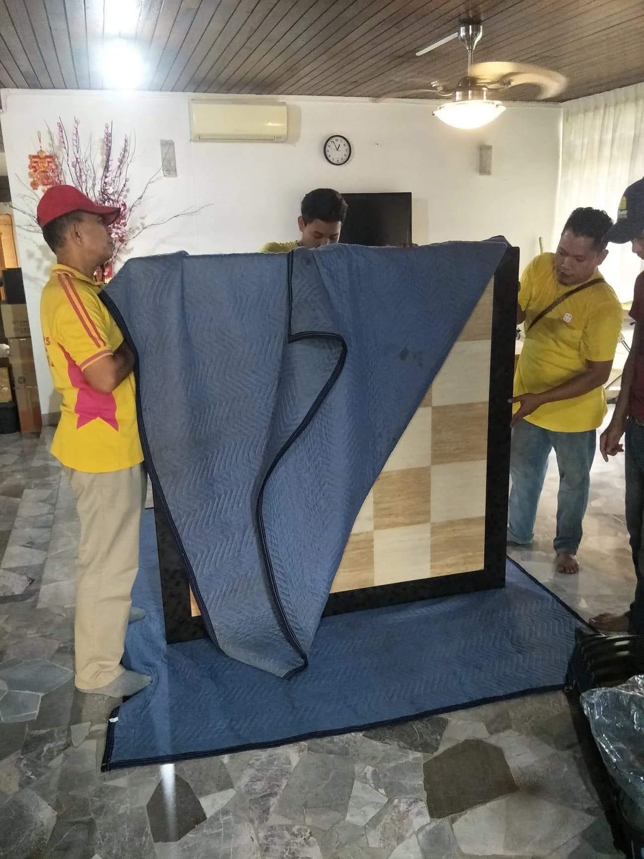 Moving company workers wrapping furniture during a relocation service