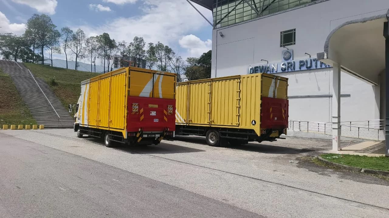 Yellow and red moving trucks parked outside IV Movers premises with company signage