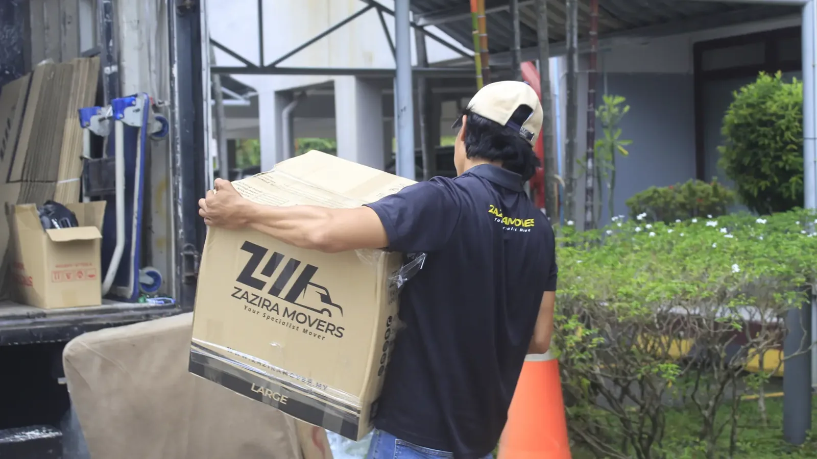 Zazira Movers worker carrying a large moving box onto a lorry during a house moving service.