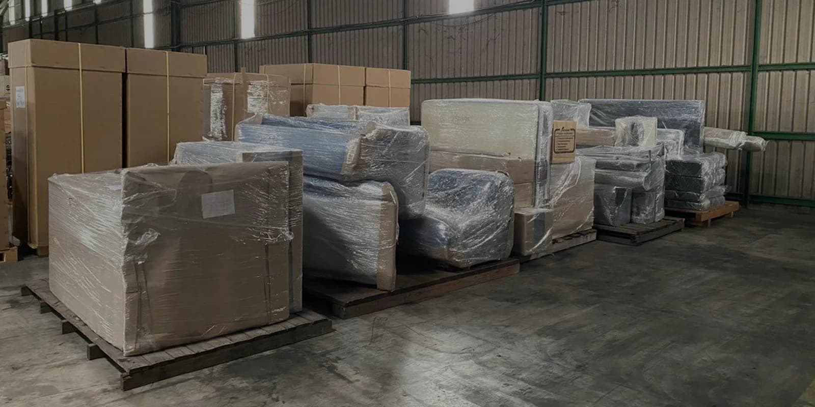 Wrapped furniture and cardboard boxes stacked on pallets in a warehouse storage facility