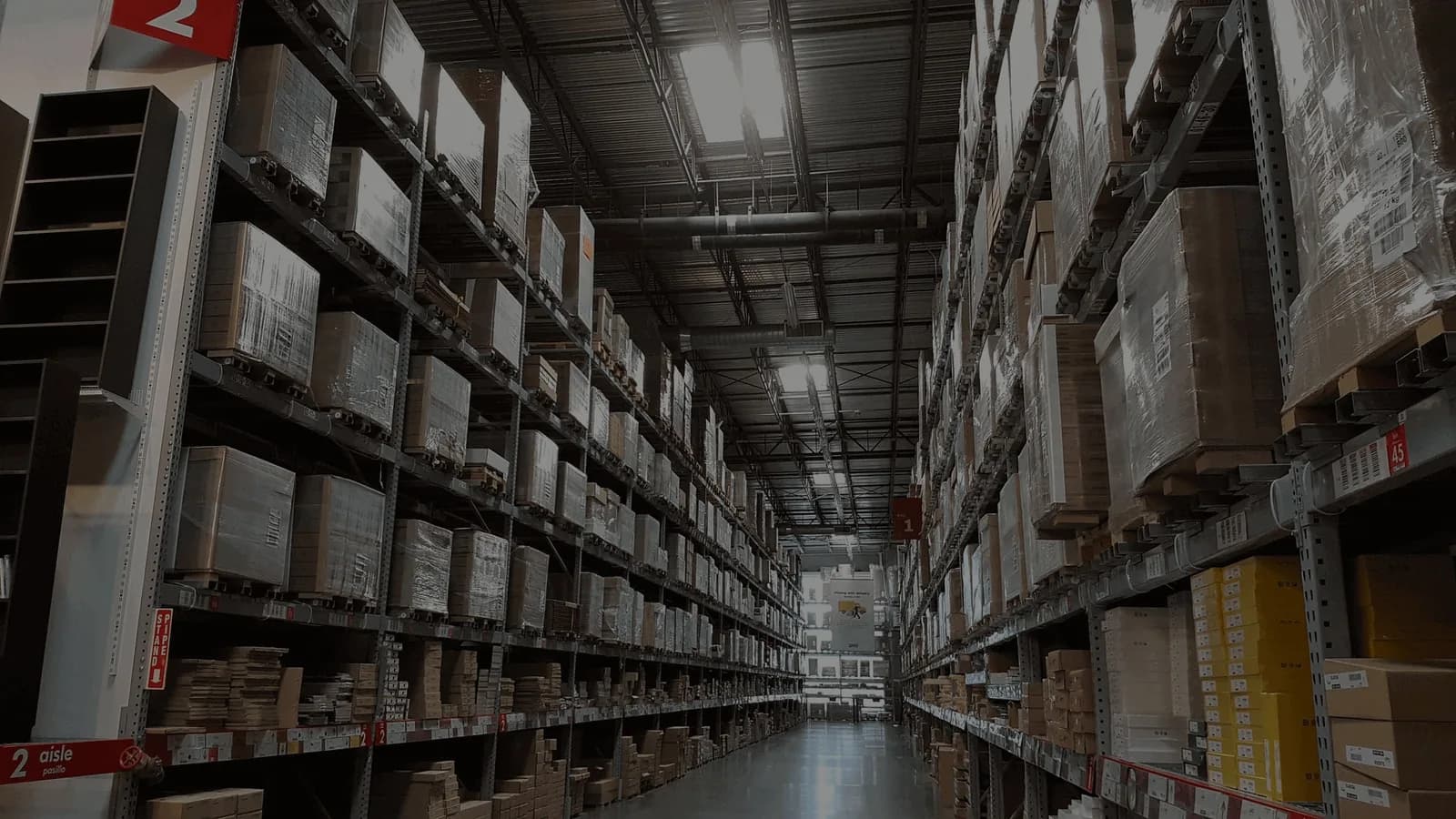 Warehouse interior with tall metal shelving units filled with cardboard boxes and packages