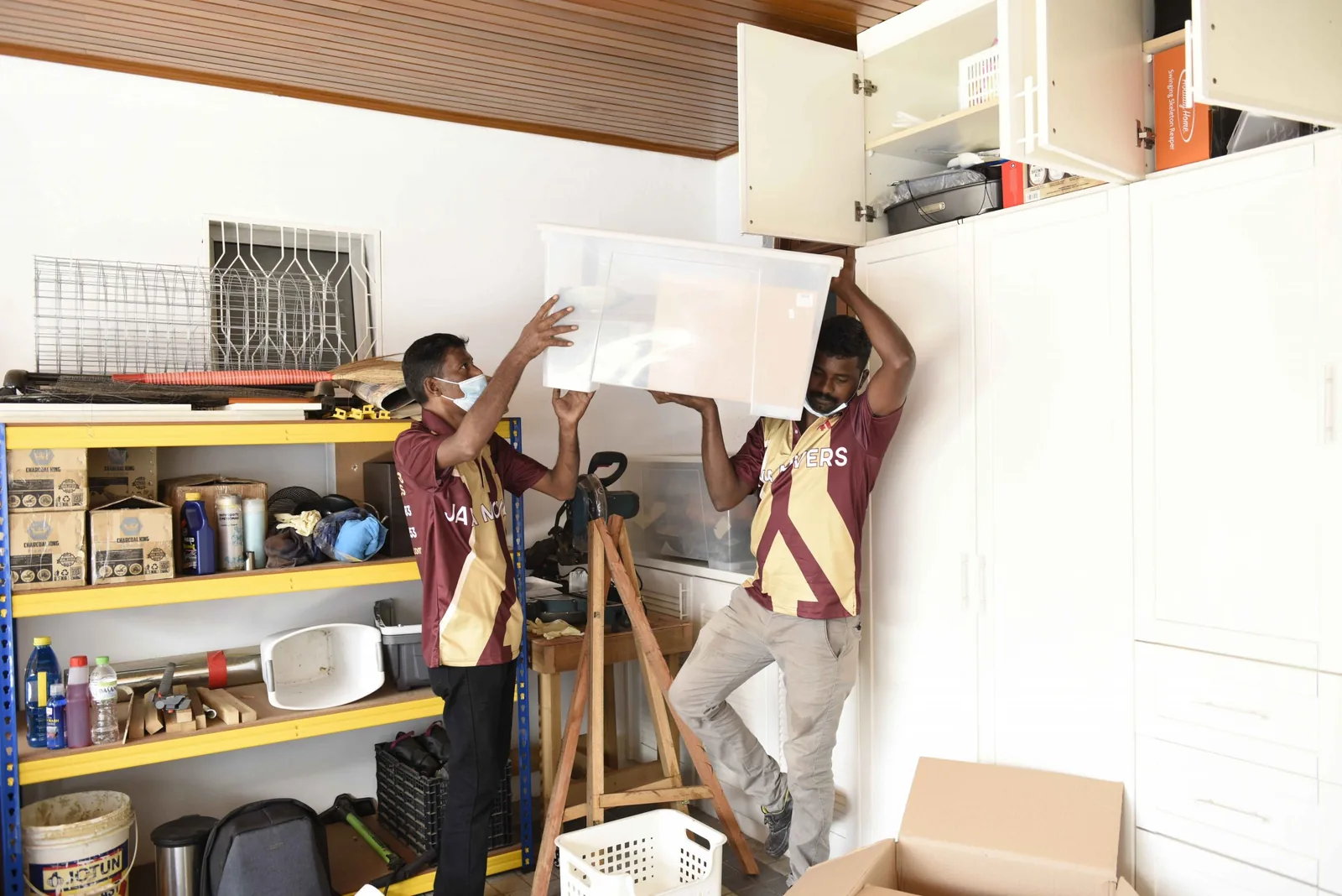 Movers in matching uniforms installing white cabinetry in a home interior
