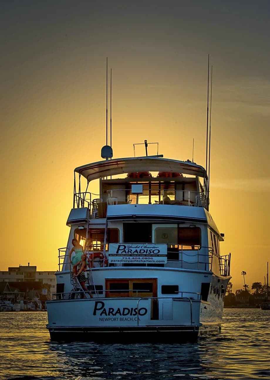 Paradiso yacht, a multi-deck blue and white charter boat, photographed at sunset in calm water