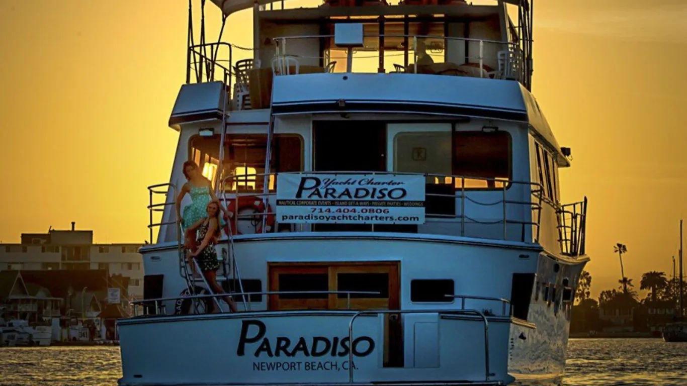 Blue and white multi-deck yacht Paradiso photographed at golden hour with calm water in background.