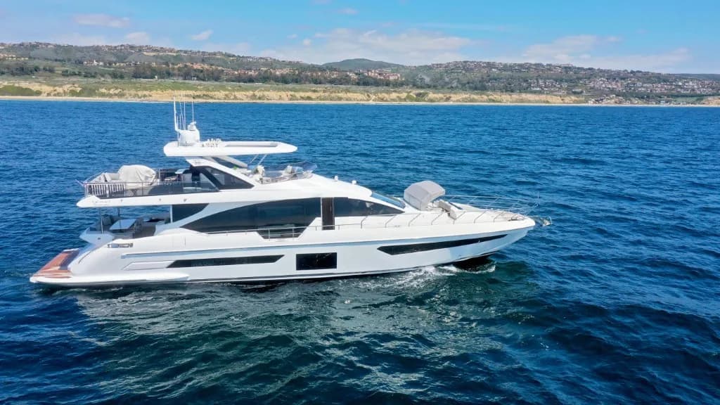 Luxury motor yacht with white hull and multiple decks anchored in blue water