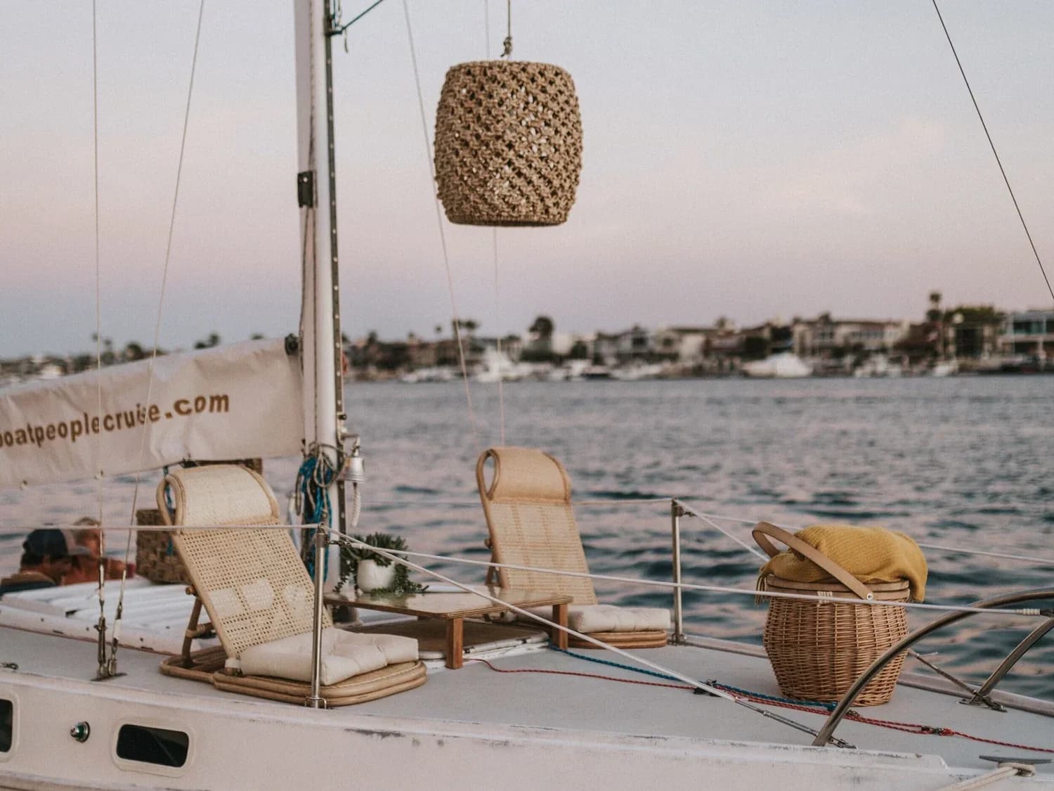 Sailboat deck with lounge chairs and woven décor, anchored in calm coastal water
