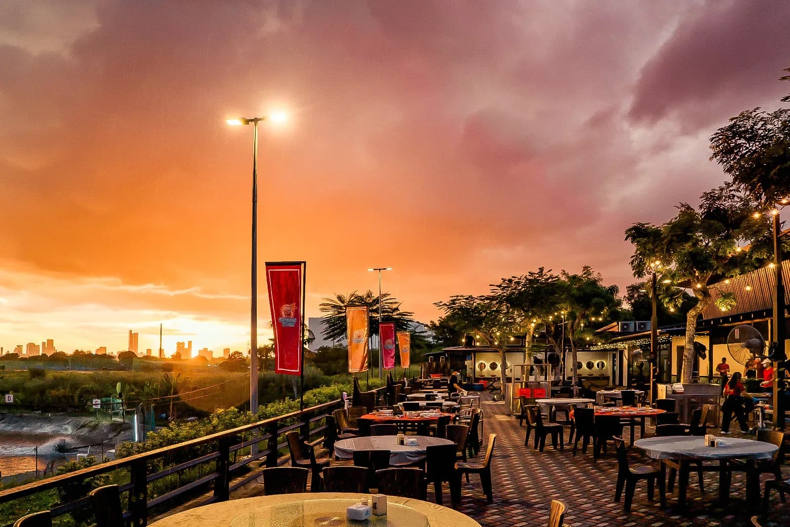 Outdoor seafood restaurant terrace at golden hour with waterfront views and city skyline