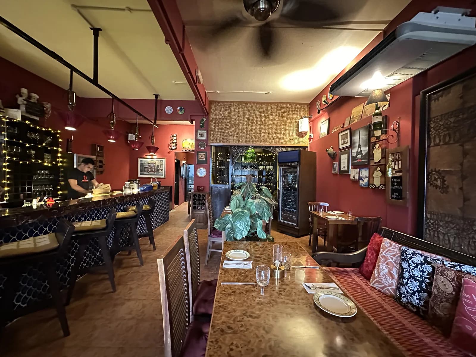 French bistro interior with red walls, set dining tables, bar counter, and ambient lighting