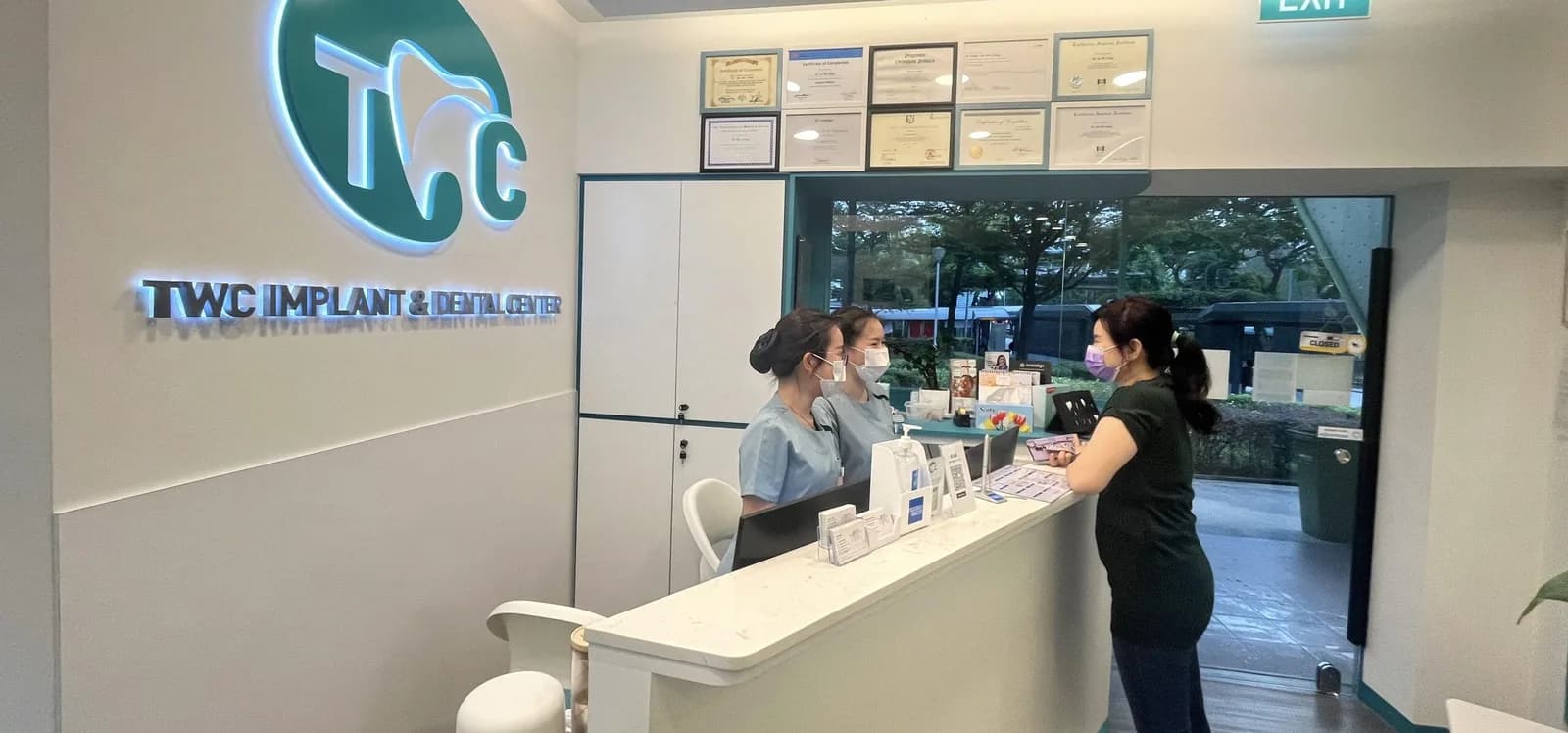 Reception desk at TWC Implant & Dental Center with staff and patient, modern dental clinic interior