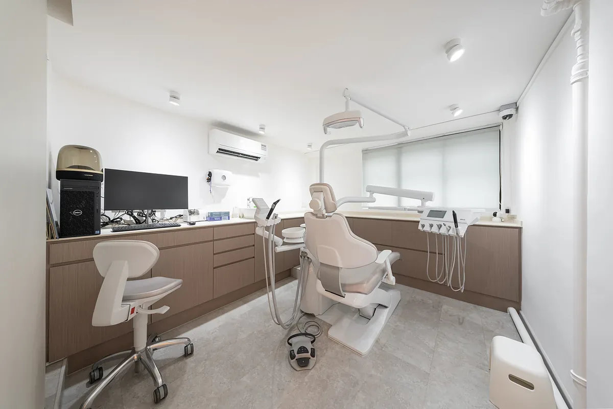 Dental treatment room with two chairs, overhead lights, and clinical equipment