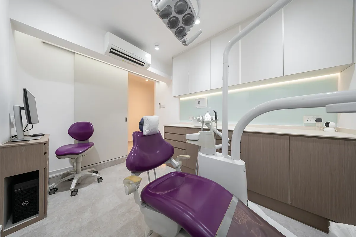 Modern dental treatment room with purple patient chairs, surgical lighting, and white cabinetry