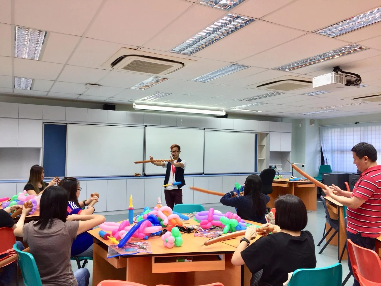 Workshop instructor guides children in a colorful classroom activity with craft materials and wooden props