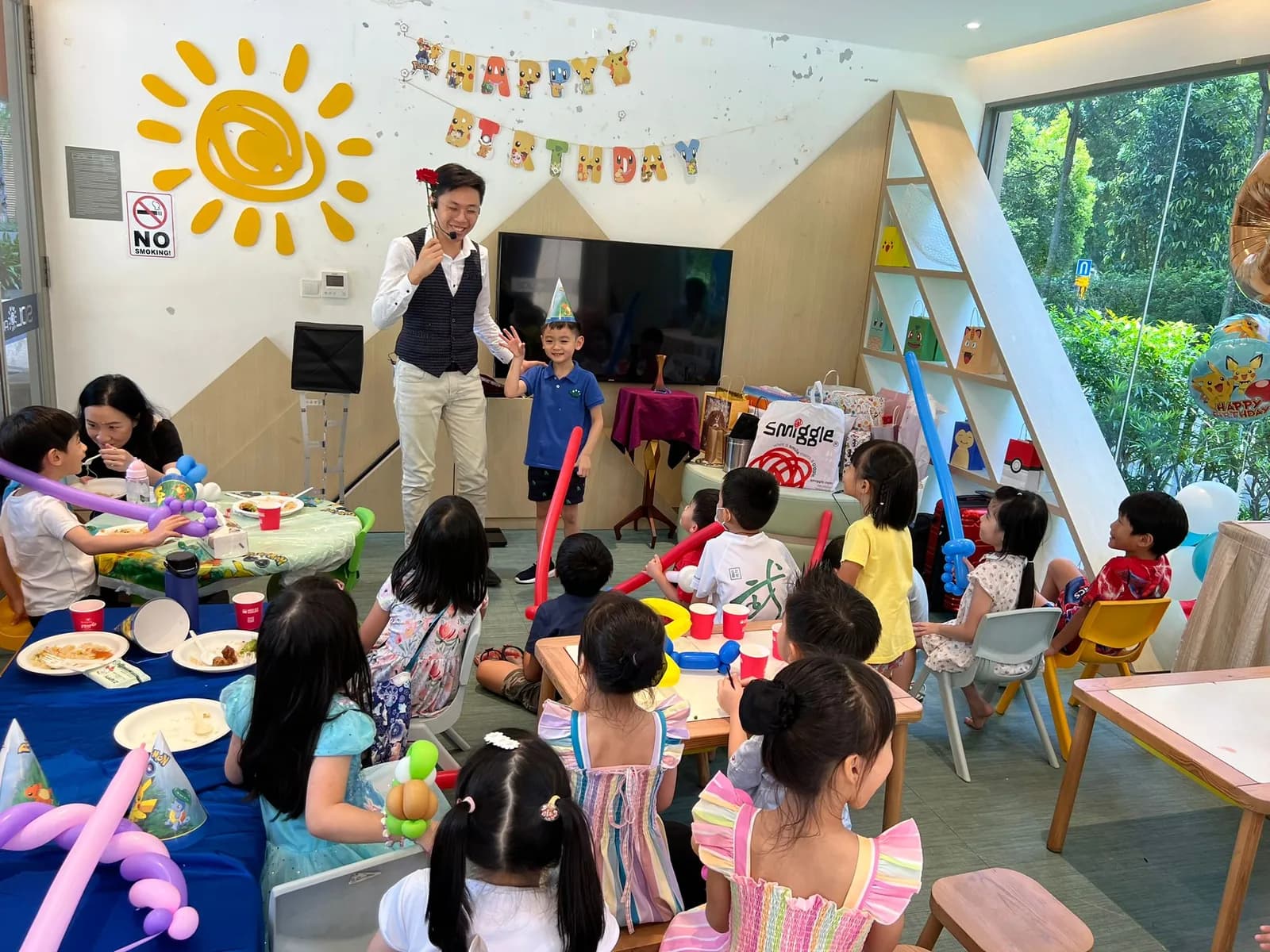 Entertainer leading children's activities at a colorful birthday party celebration with decorated venue