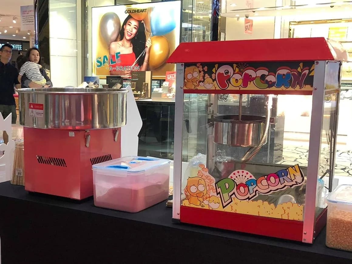 Red popcorn and candy floss machines with colorful graphics at an event venue