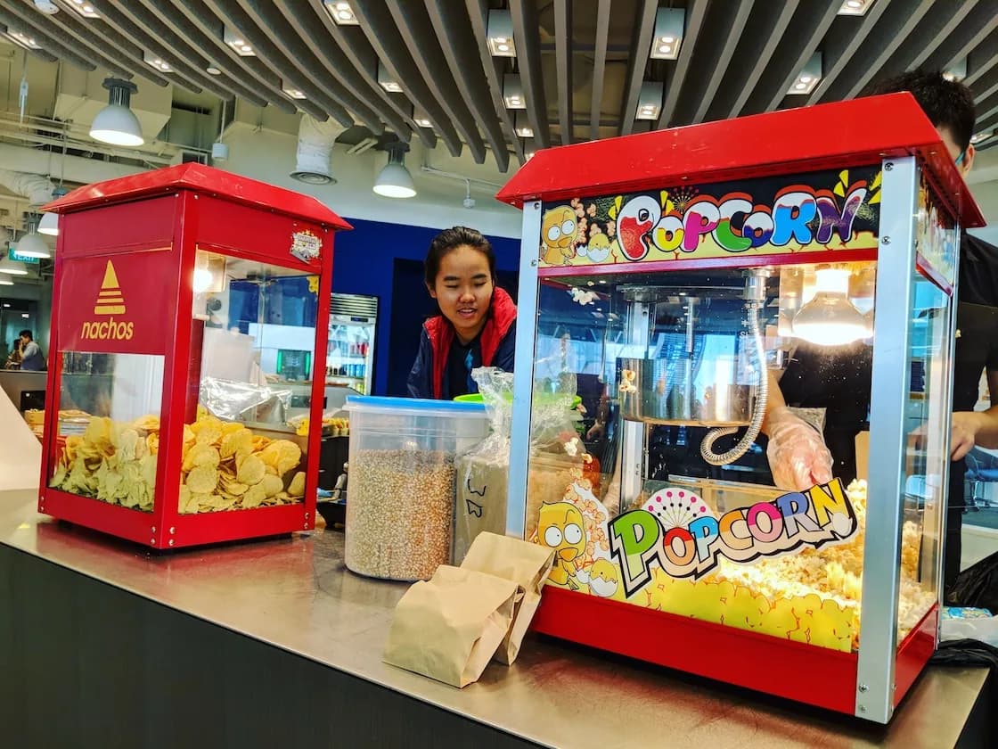 Red popcorn and nachos kiosks with staff member at event venue
