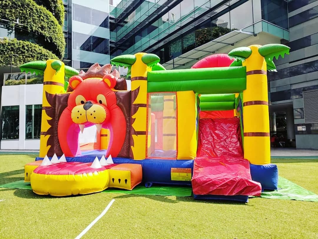Colorful lion-themed inflatable bounce house and slide on grass outdoor venue