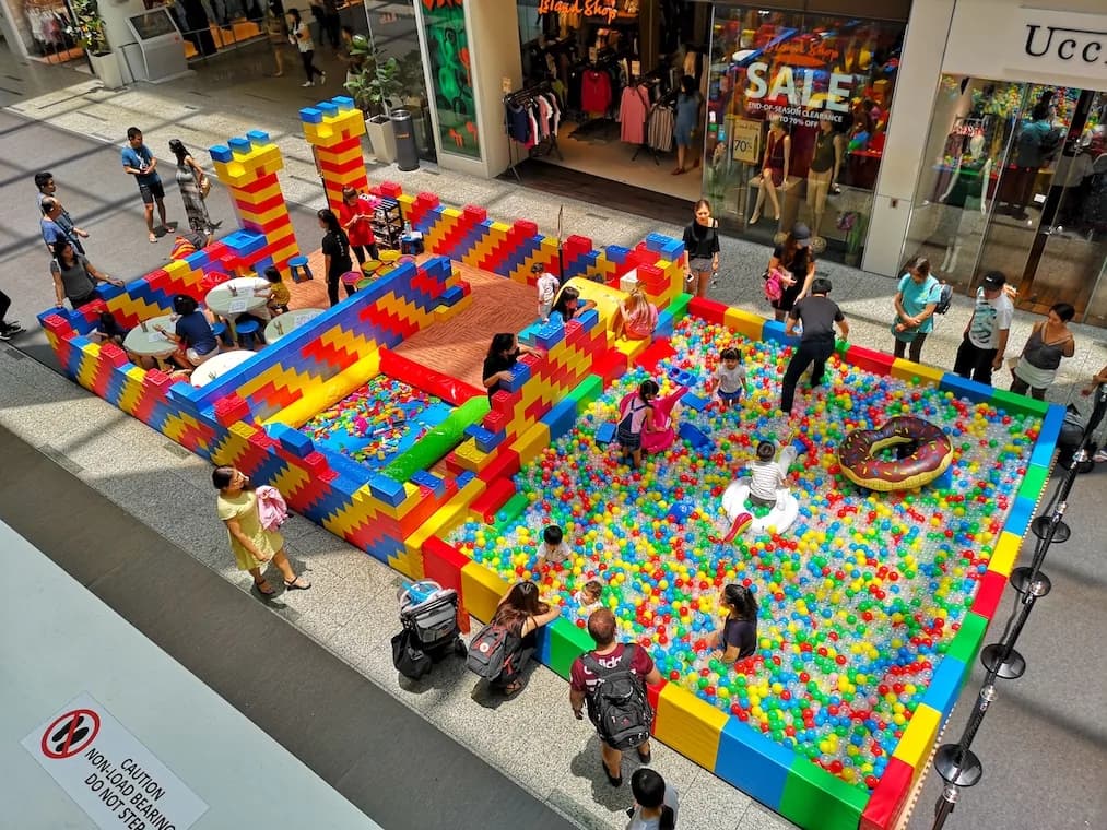 Children playing in a large ball pit with colorful building blocks and obstacles