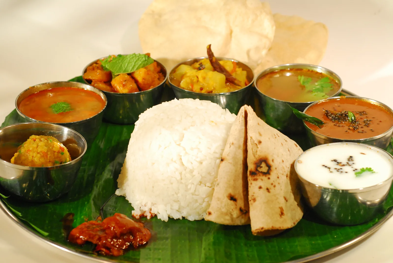 South Indian thali with idli, dosa, rice, curries and chutneys on banana leaf