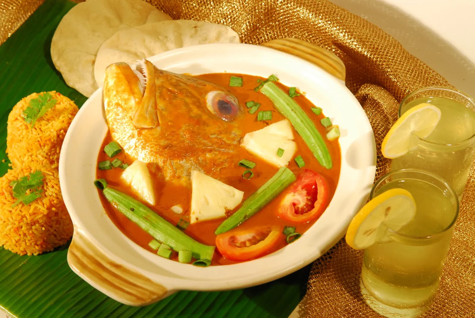 Whole fried fish in red curry soup with tofu and vegetables, served with rice cakes and drinks