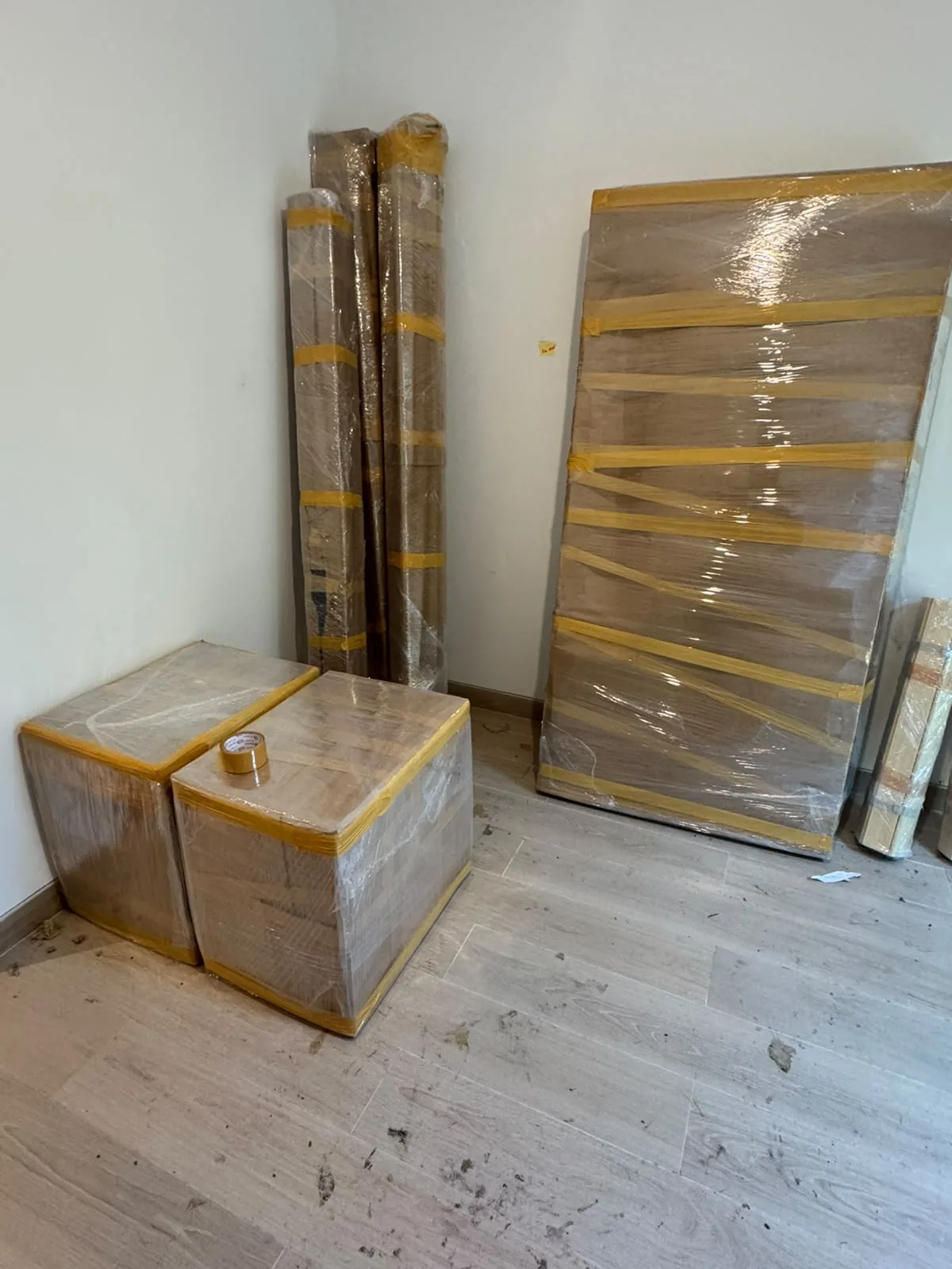 Wrapped furniture pieces secured with yellow tape ready for moving