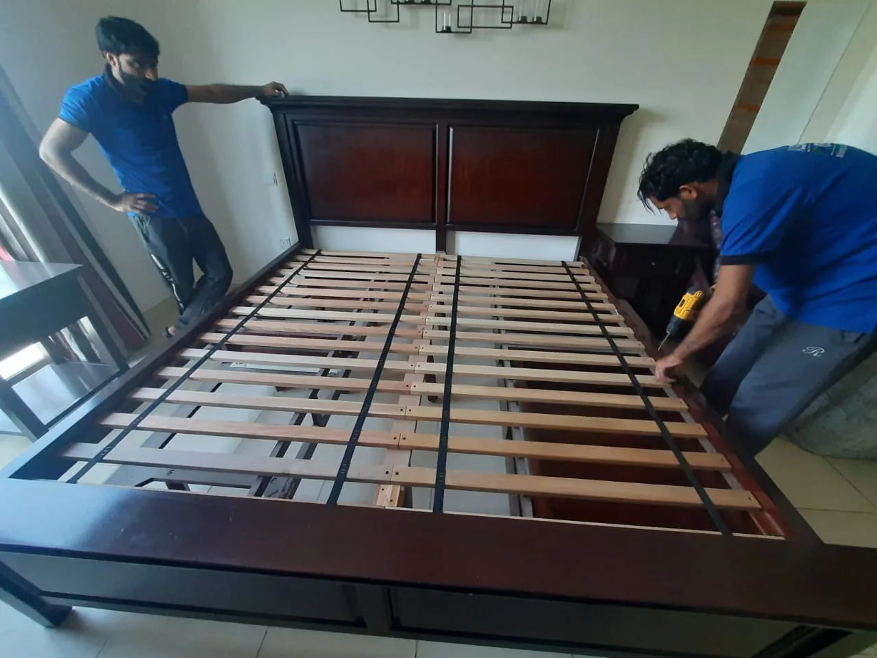 Workers assembling a bed frame during a moving and installation service.