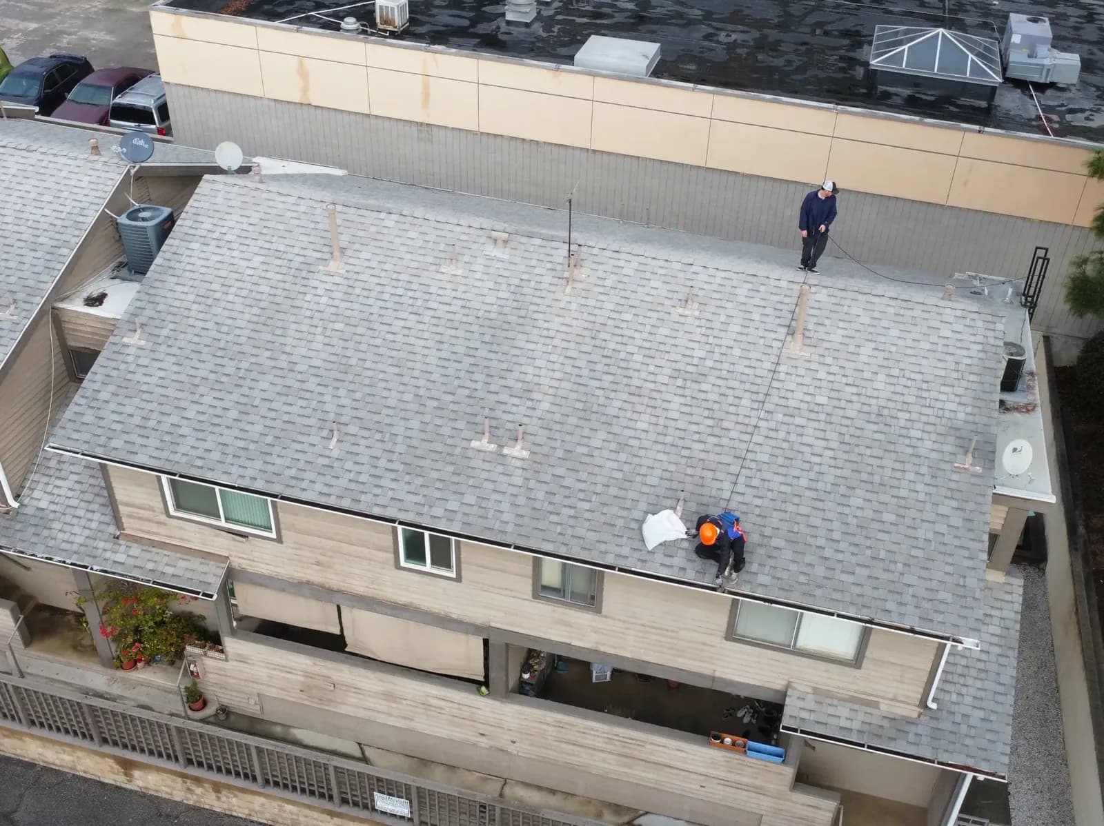 Two gutter cleaners working on a residential roof with tools and equipment