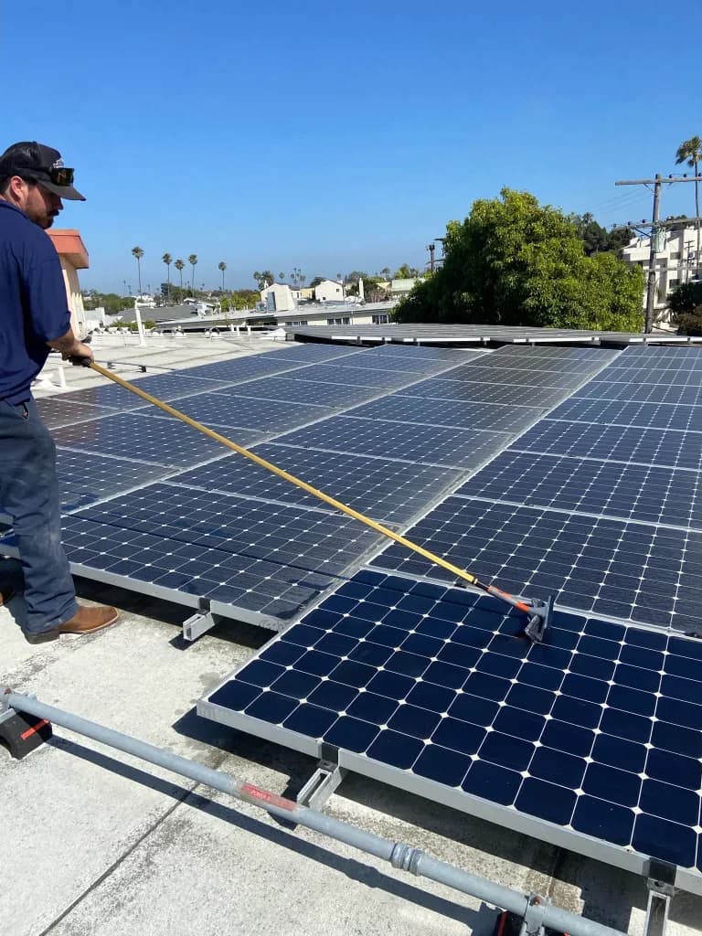 Technician with measuring tape inspecting rooftop solar panels on flat commercial roof