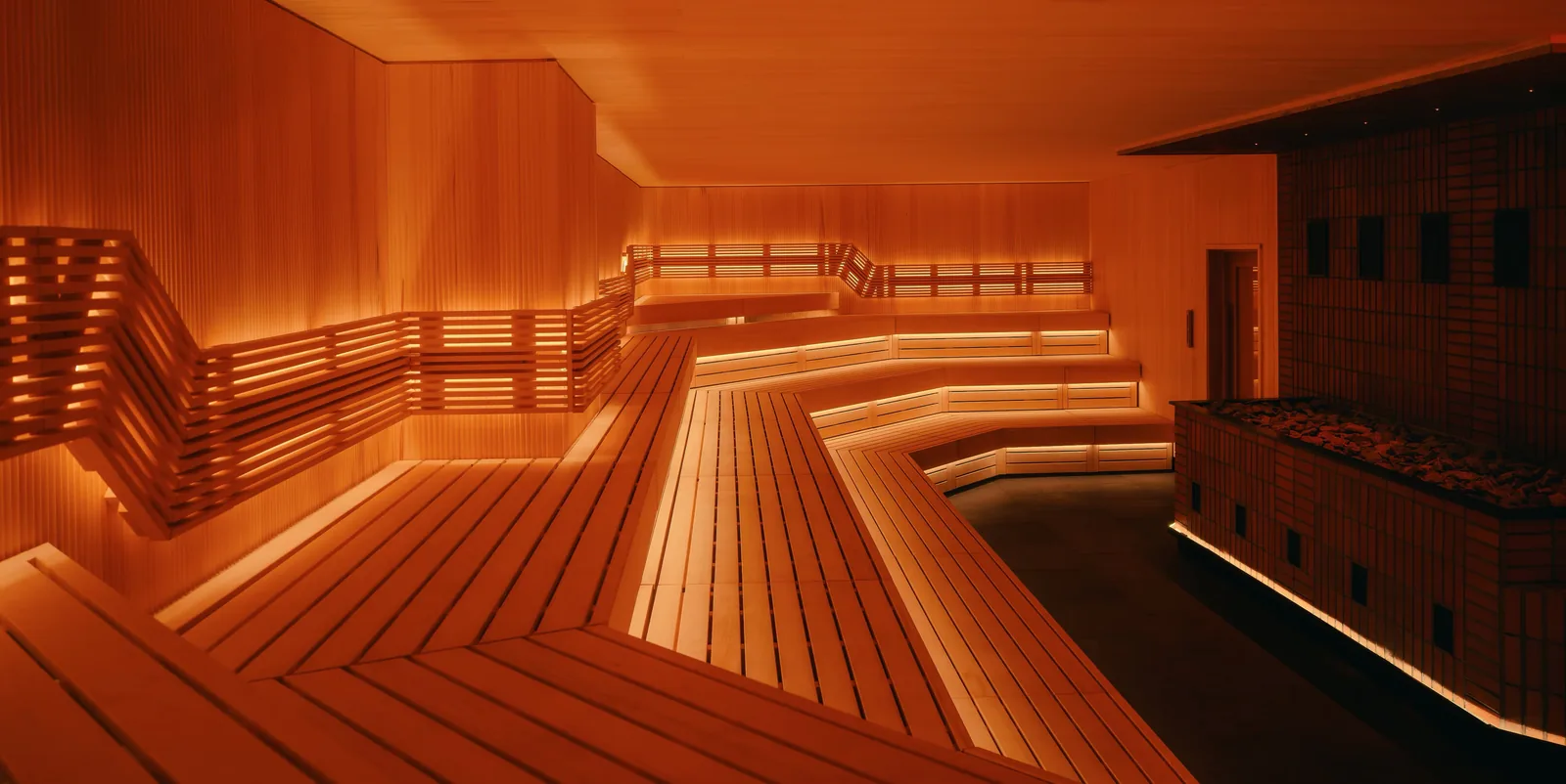 Modern sauna with wooden benches, tiered seating, and warm ambient lighting