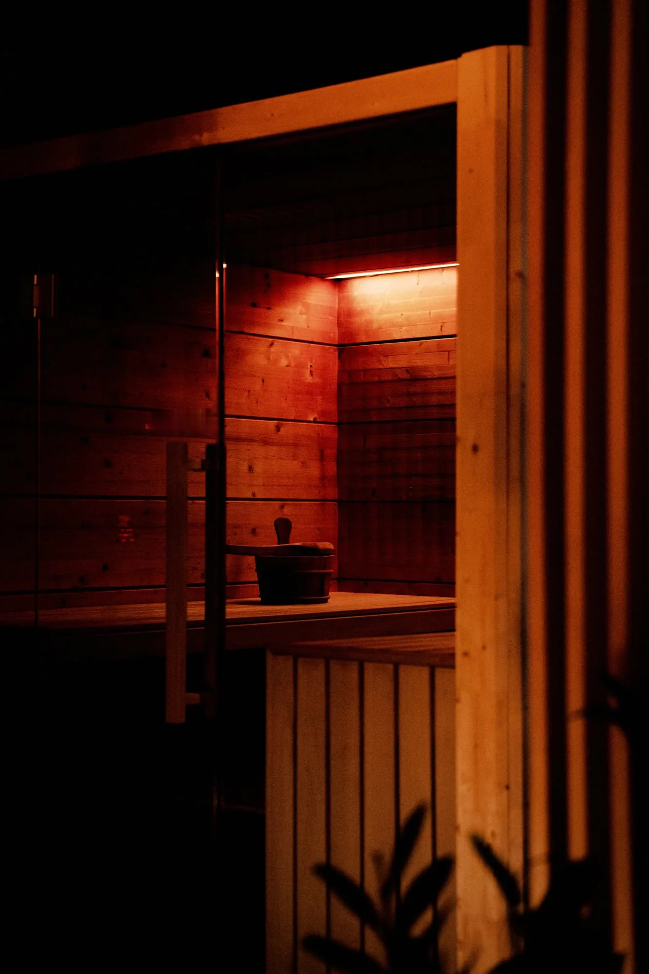 Sauna interior with wooden walls and benches, illuminated by warm amber lighting