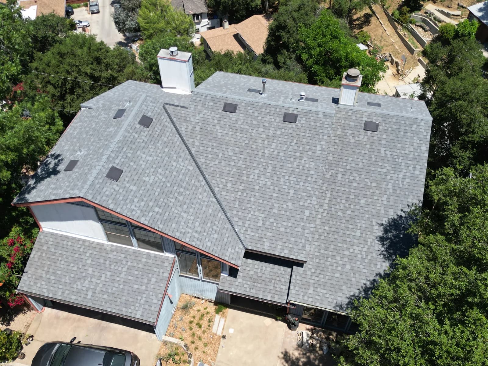 Aerial view of a newly installed gray asphalt shingle roof on a residential home