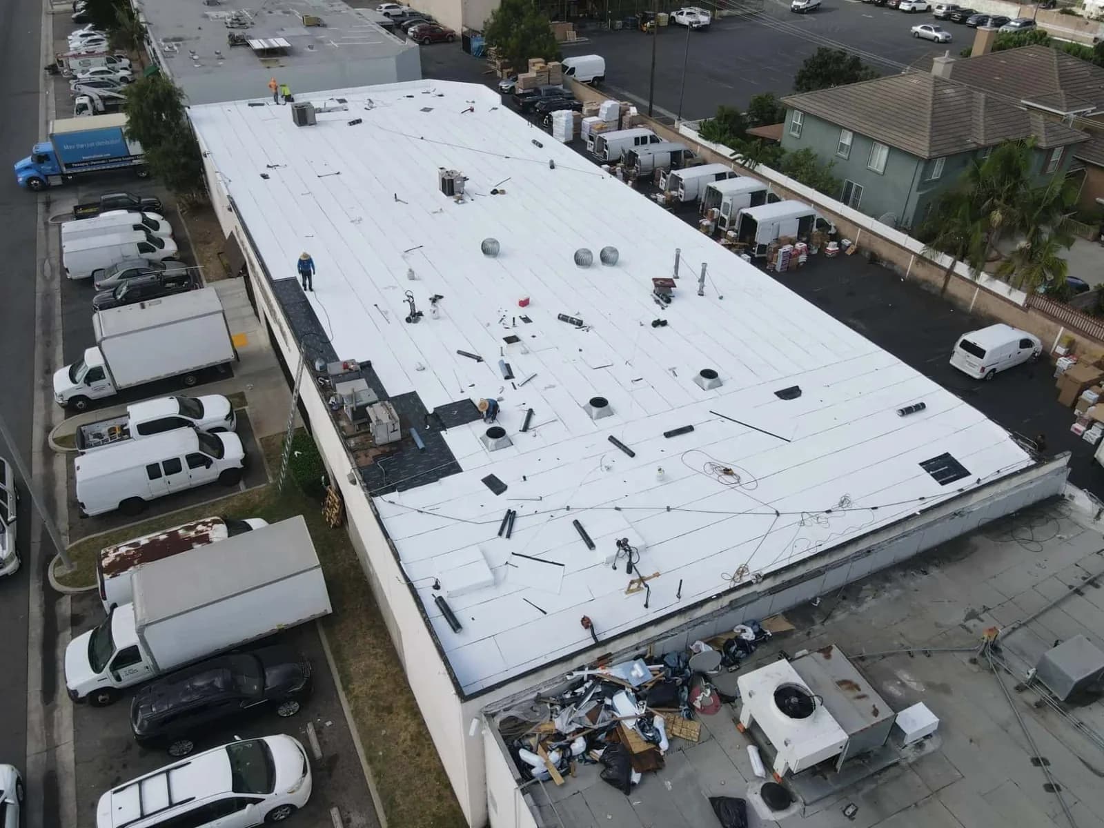 Commercial roofing project with white membrane, HVAC units, and work crew from above