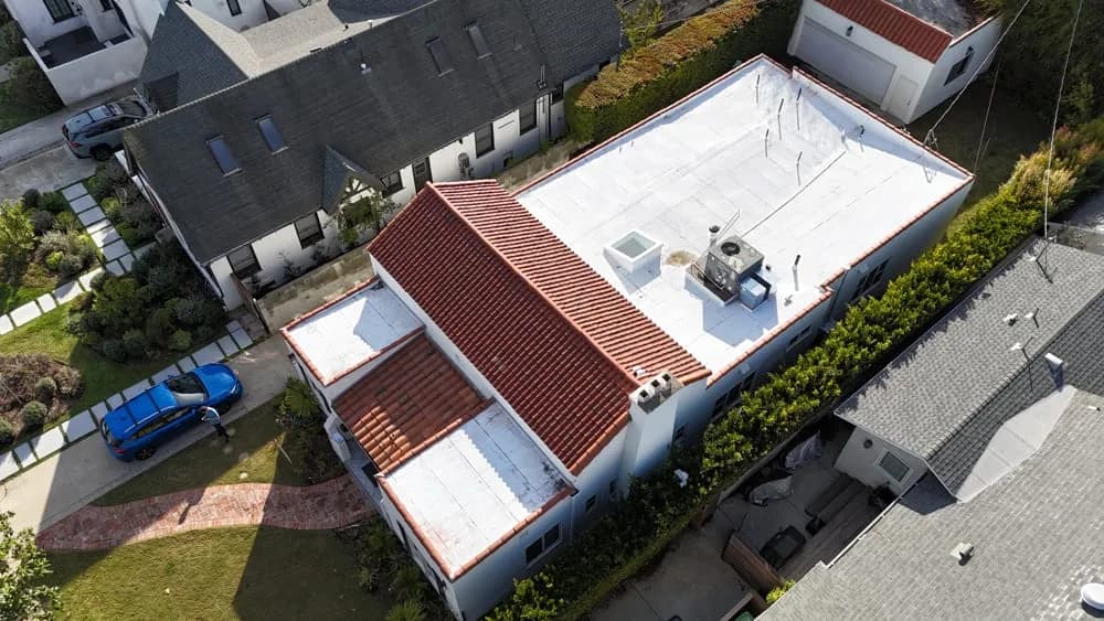 Aerial view of house with new red tile and white membrane roofing installed