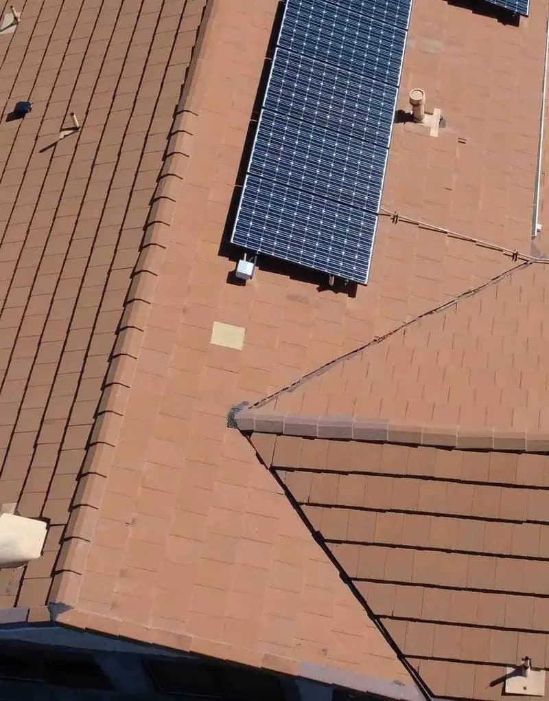 Aerial view of tile roof with installed solar panel array and electrical infrastructure
