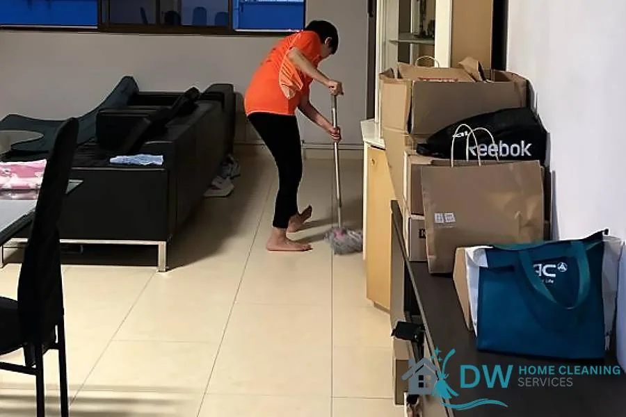 Worker mopping and cleaning a light tile floor indoors