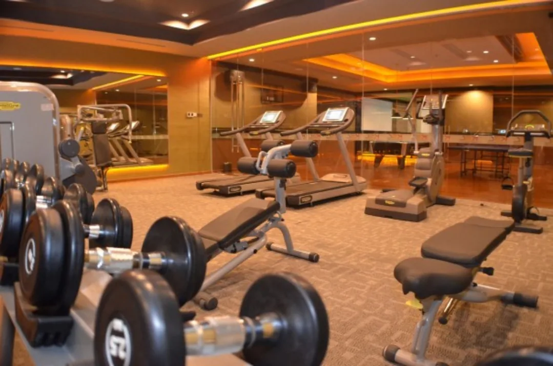 Modern gym with free weights, cardio equipment, and exercise machines under warm ambient lighting