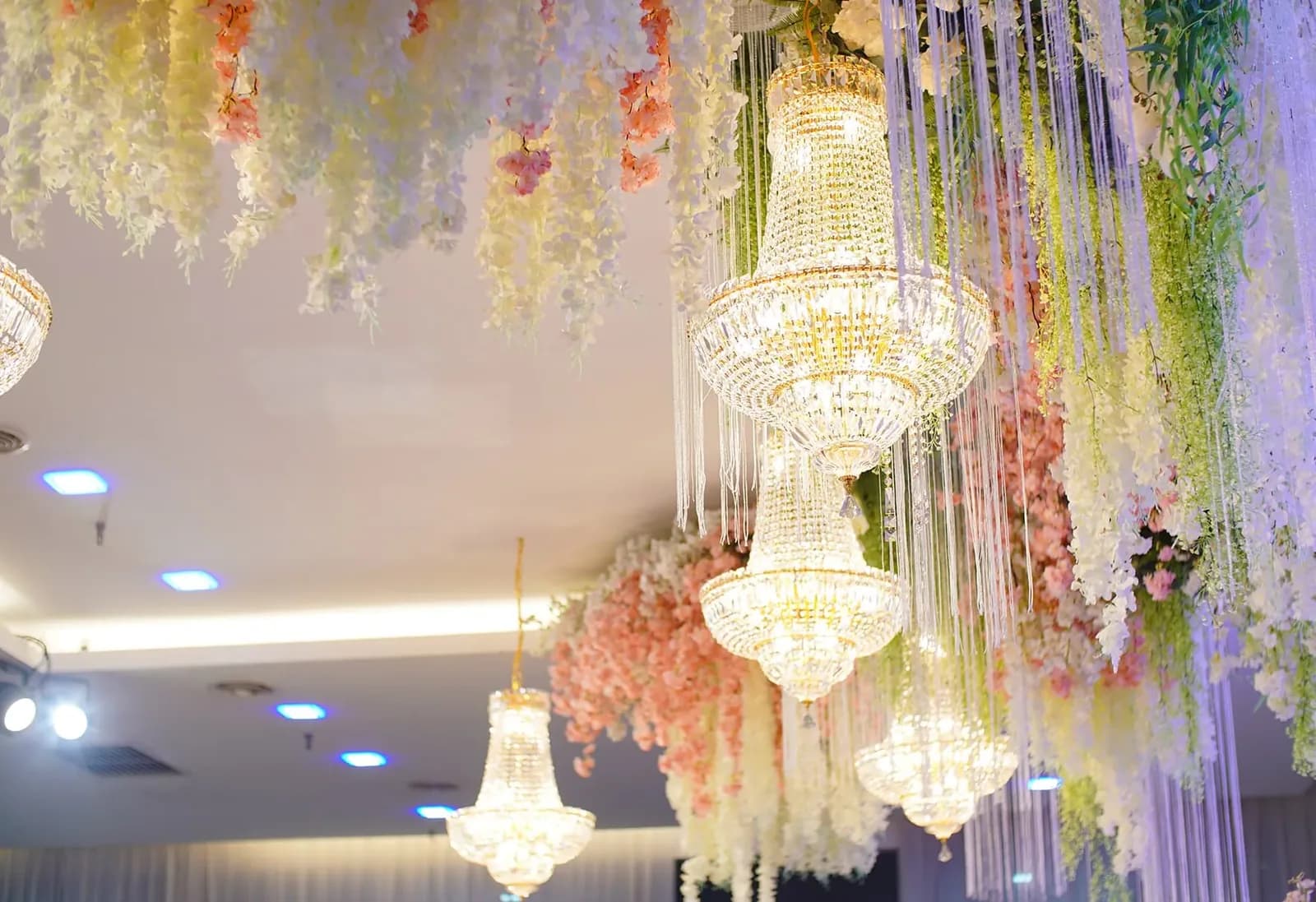 Elegant wedding venue with crystal chandeliers and hanging floral arrangements in soft colors