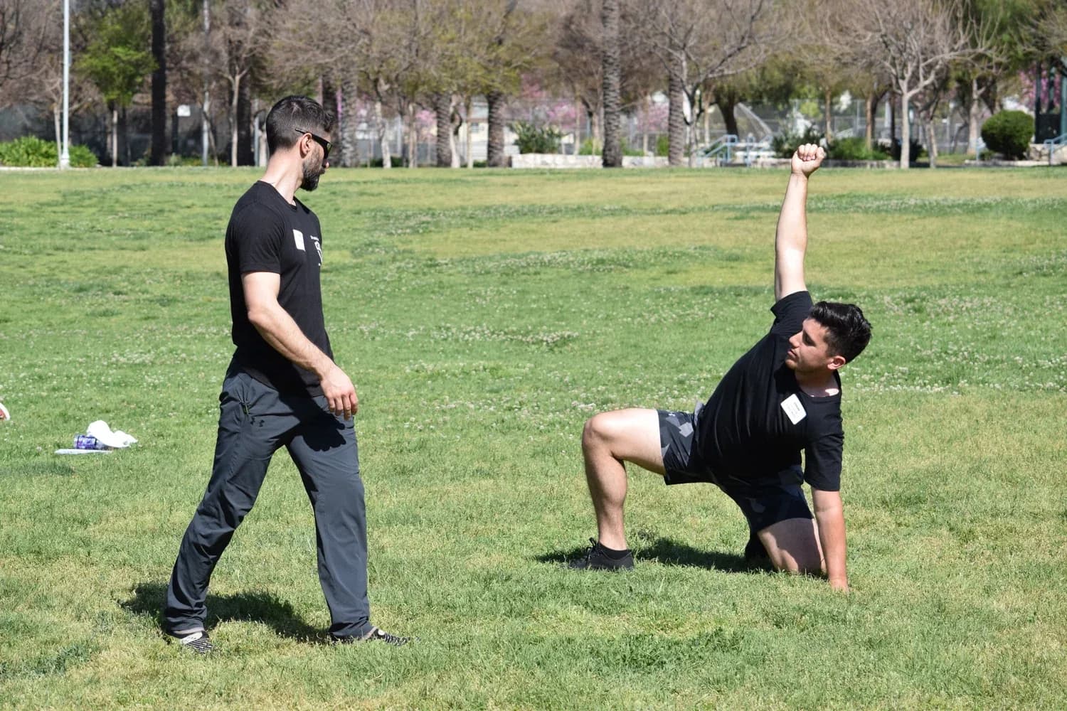 Physical therapist observing client doing an outdoor balance exercise on grass