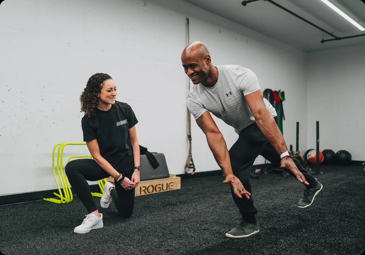 Personal trainer demonstrating exercise technique to client in gym studio