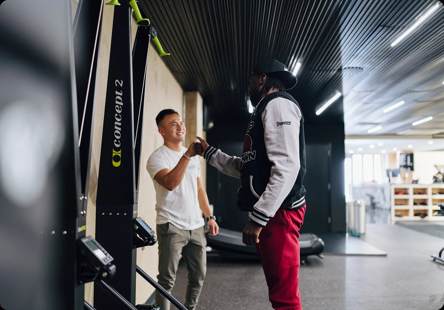 Trainer assists client with suspension training exercise in modern physical therapy clinic