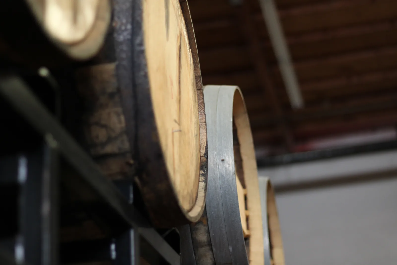 Wooden barrels lined up in a dim cellar with metal bands