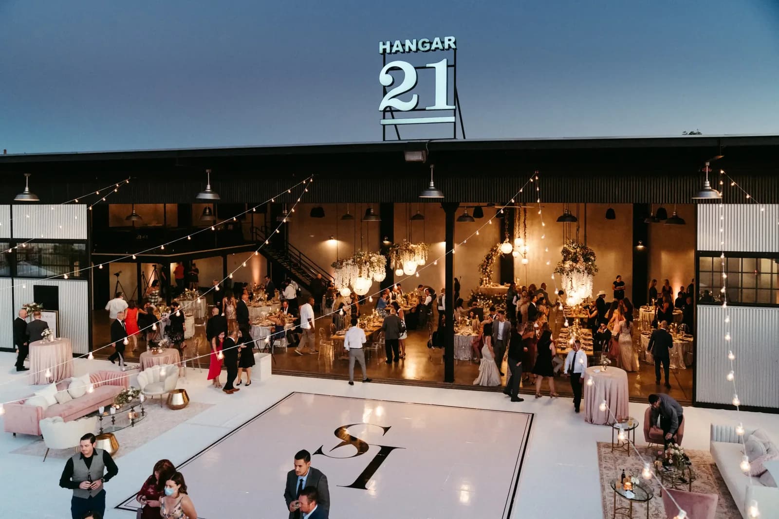 Hangar 21 event venue with decorated dance floor, dining tables, and guests in formal wear