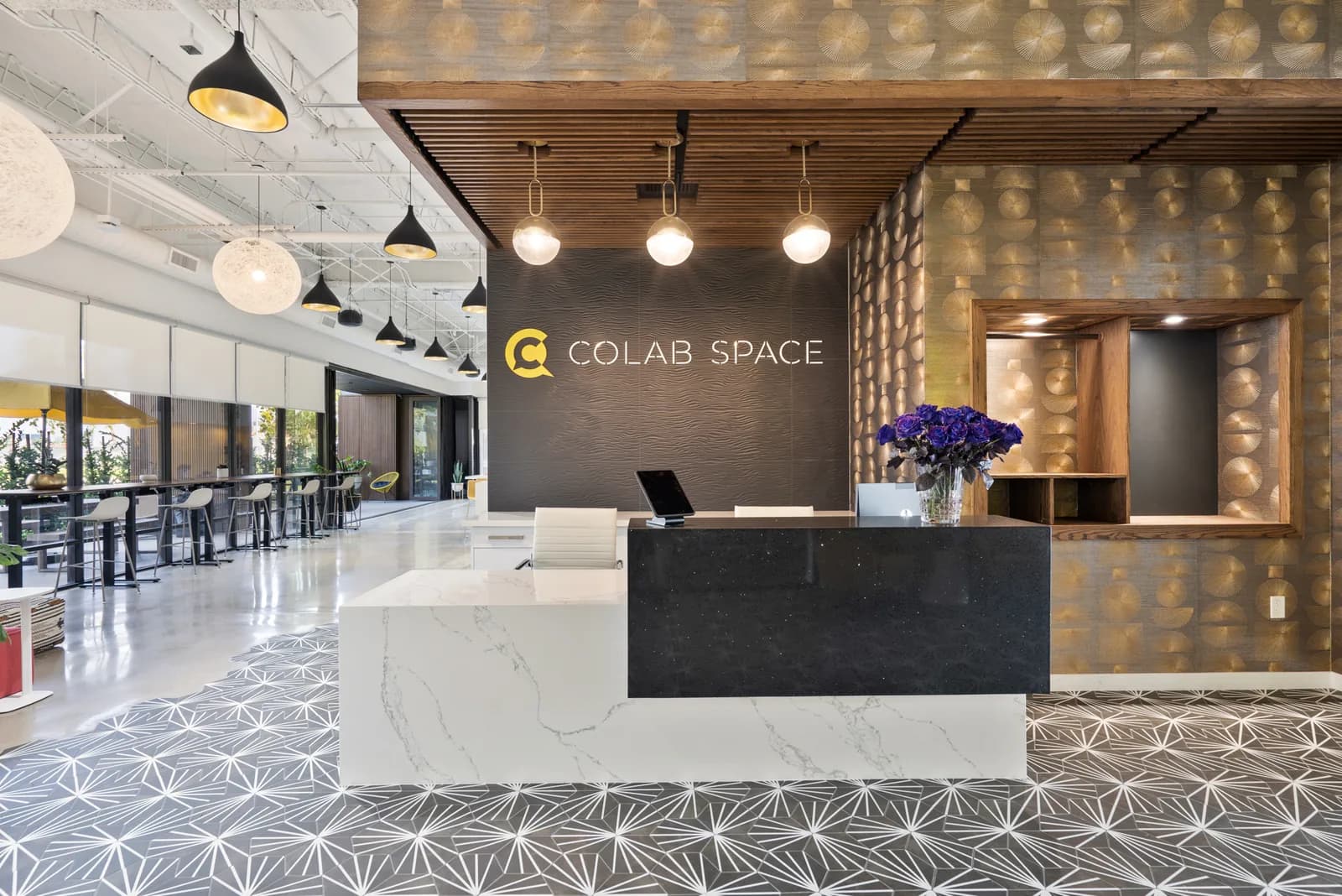 Modern reception desk at Colab Space with black and white marble counters, pendant lights, and branded wall signage