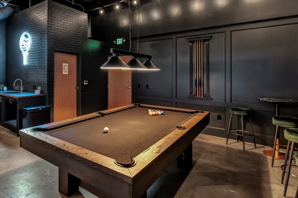 Pool table in upscale billiards lounge with dim lighting and bar seating