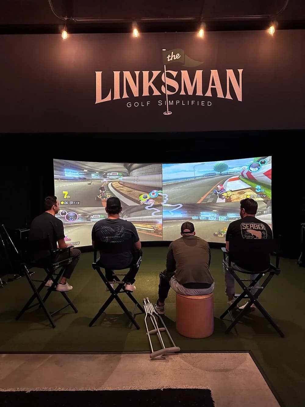 Golf simulator bay at The Linksman with four players using motion-capture technology on large screens