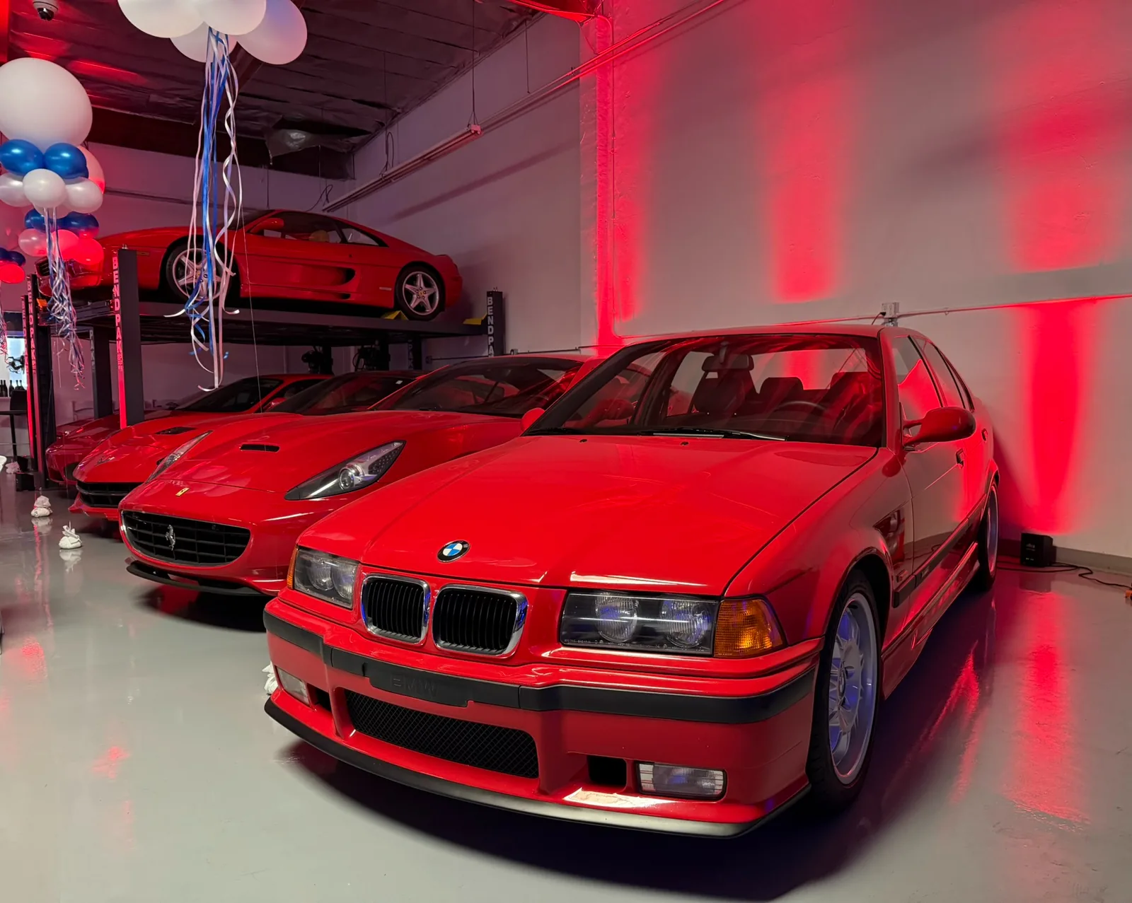 Red sports cars displayed in an illuminated showroom with balloons and modern event space